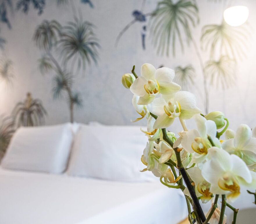 Letto con cuscini bianchi e fiori di orchidea.