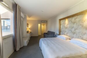 Camera d'albergo luminosa con letto matrimoniale e divano.