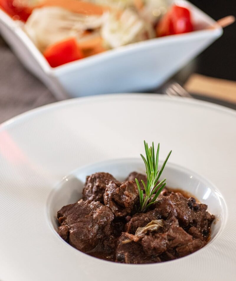 Stufato di carne con rosmarino, insalata e vino.